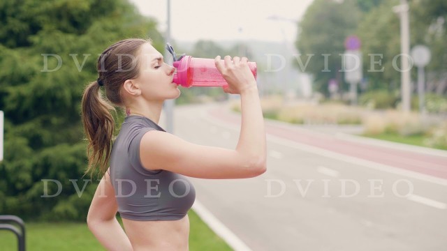 'Fitness woman drinking water from bottle while sport training outdoor'
